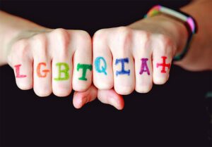 LGBTQIA+ letters in rainbow letters across the knuckles of 2 hands